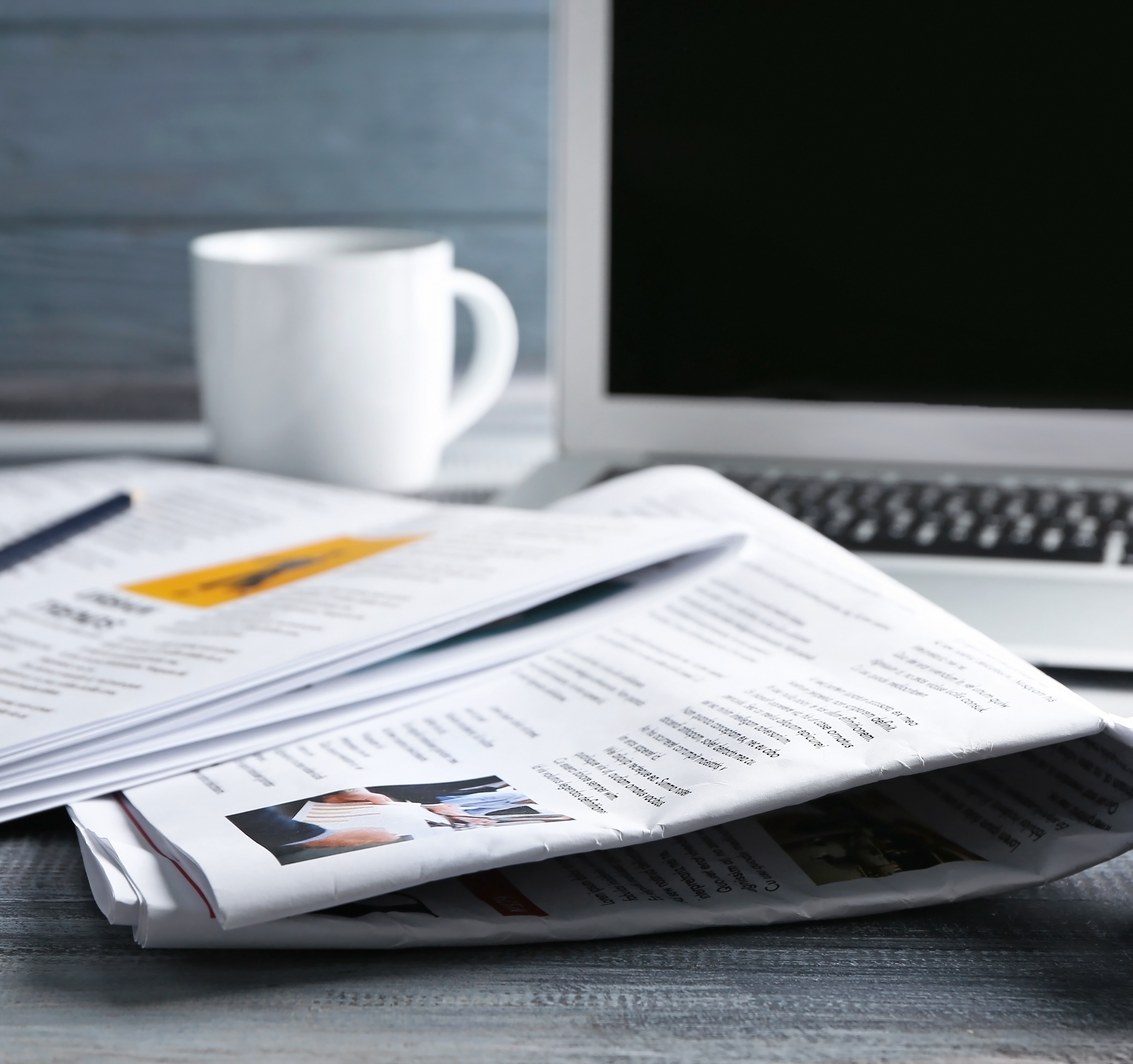 Image of a coffee cup, newspaper, and laptop