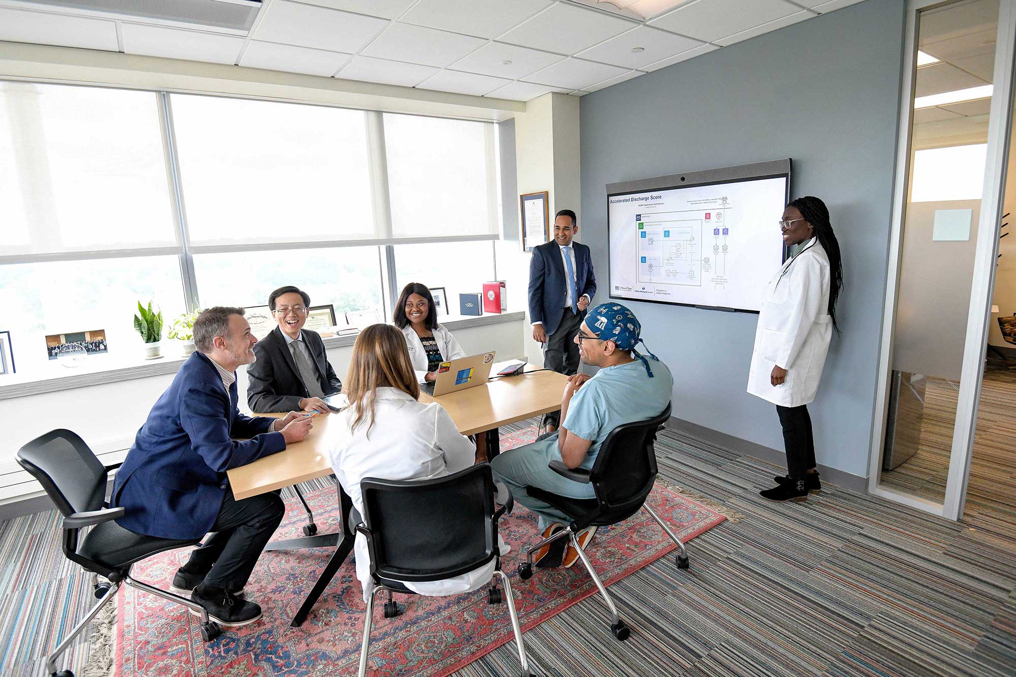 Faculty at an office table reviewing a projected diagram