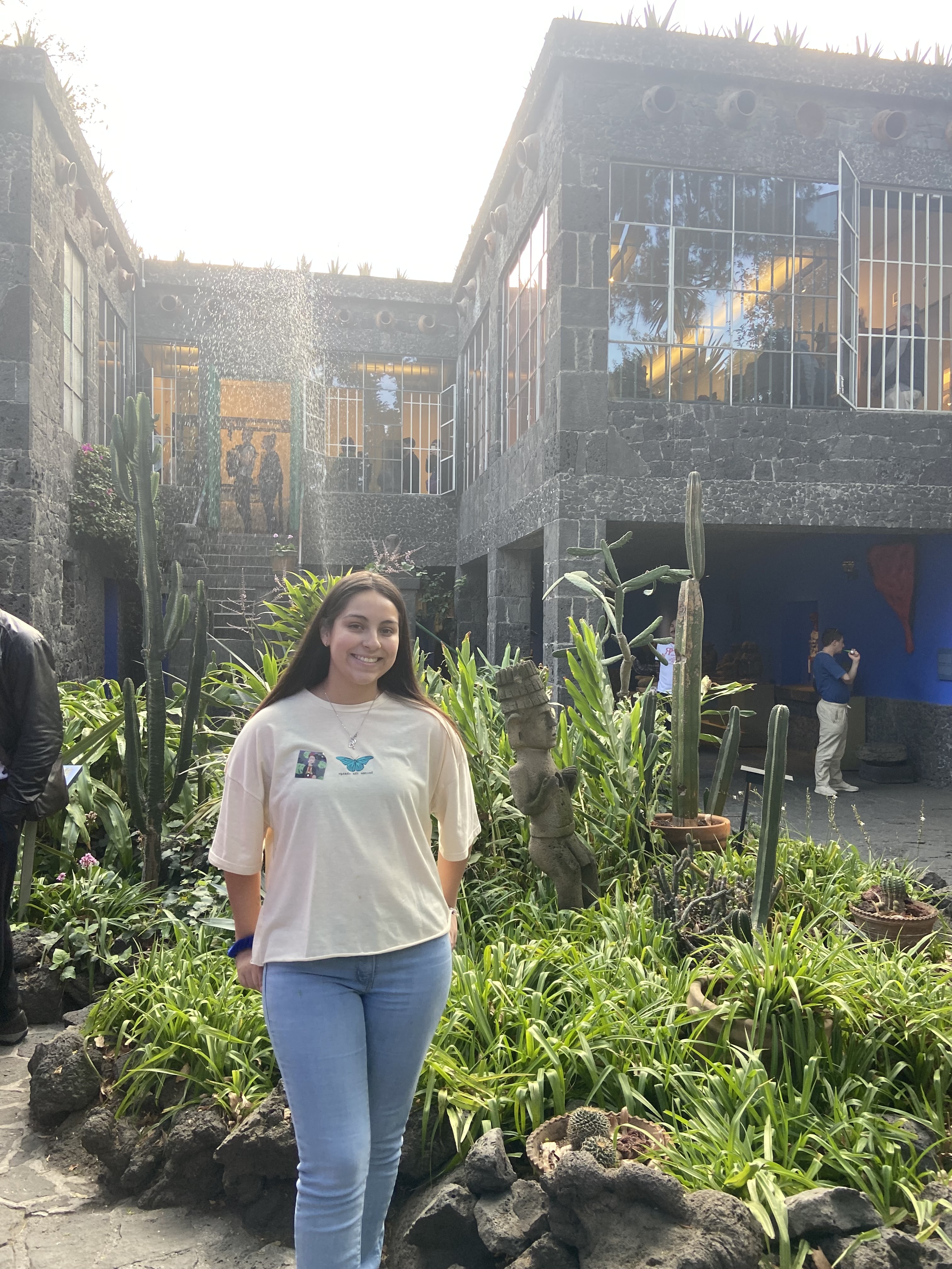 A woman smiling and standing in a courtyard full of plants