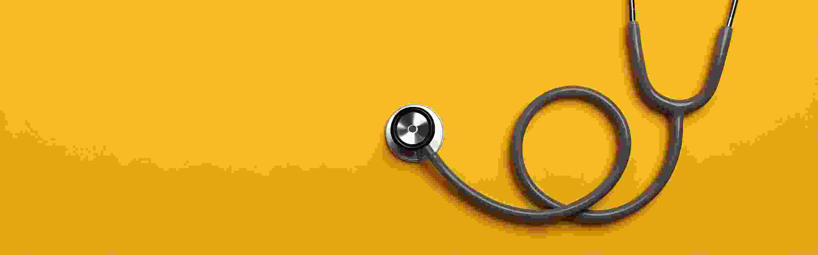 Curled up stethoscope on a plain yellow background