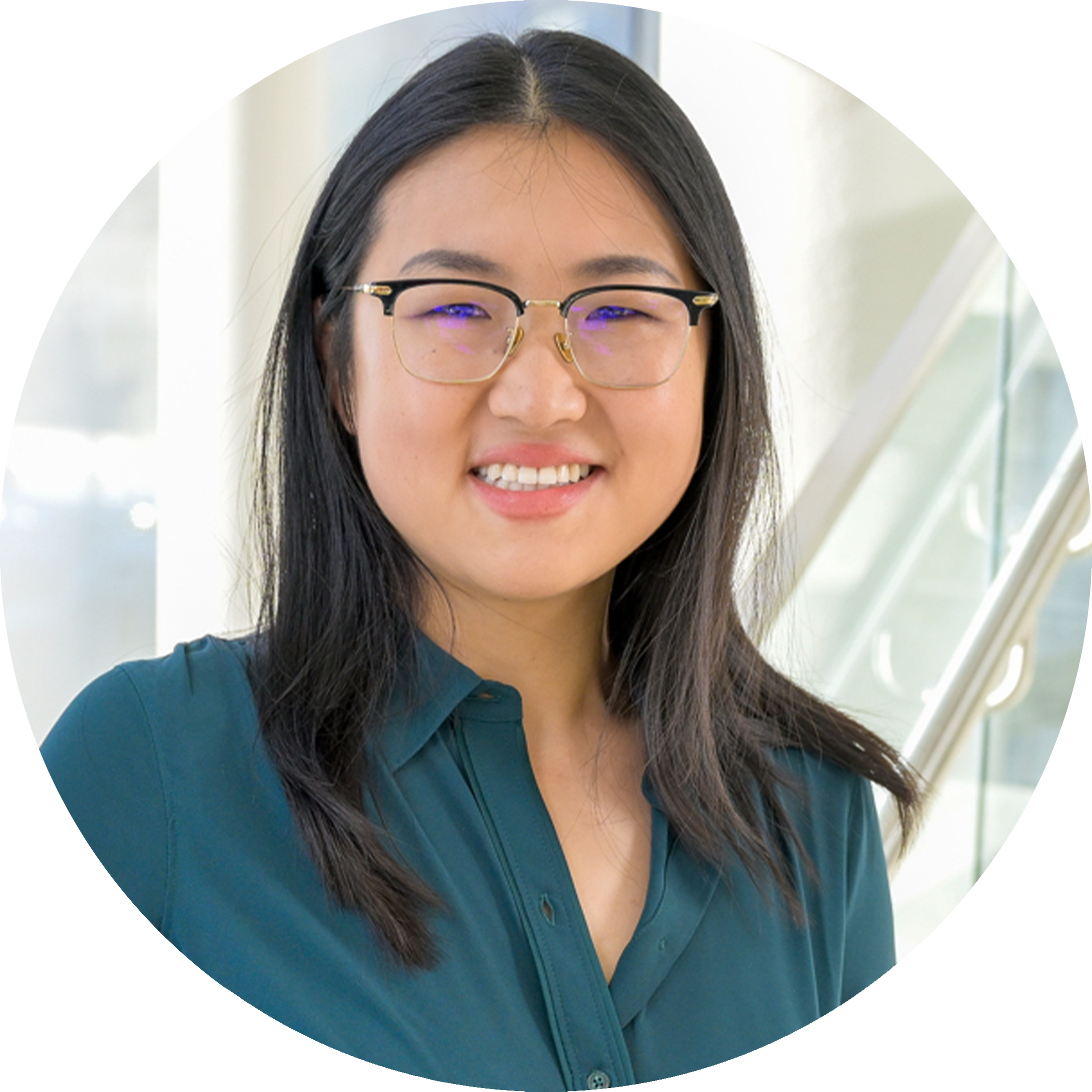 A headshot of Qinglan Ling, wearing glasses and a smile. She is wearing a teal blouse in a pose in front of a large window in the background.