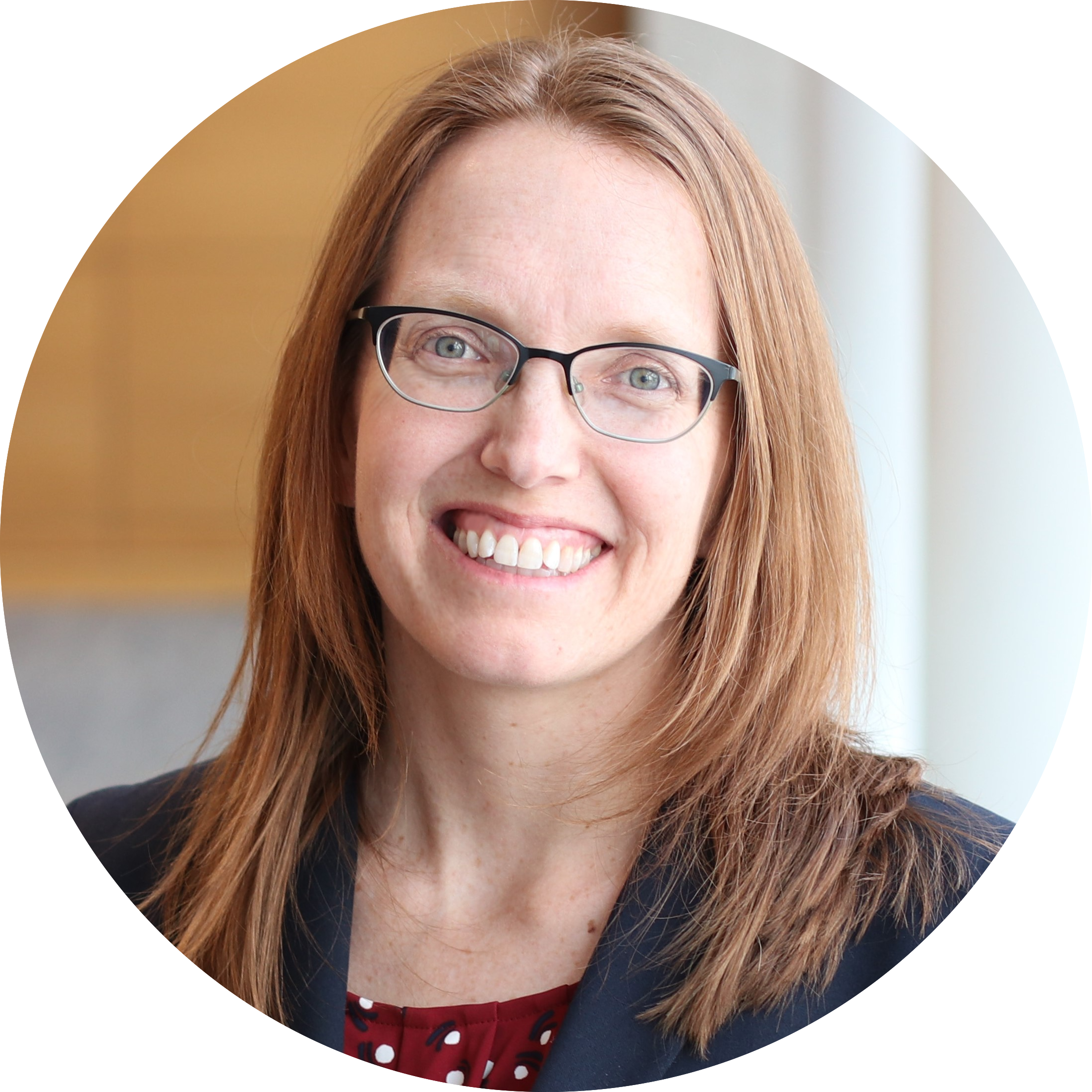 Circular portrait of Dr. Cynthia Fuhrmann, who has shoulder-length red-brown hair. She is wearing glasses and a dark blazer and is smiling