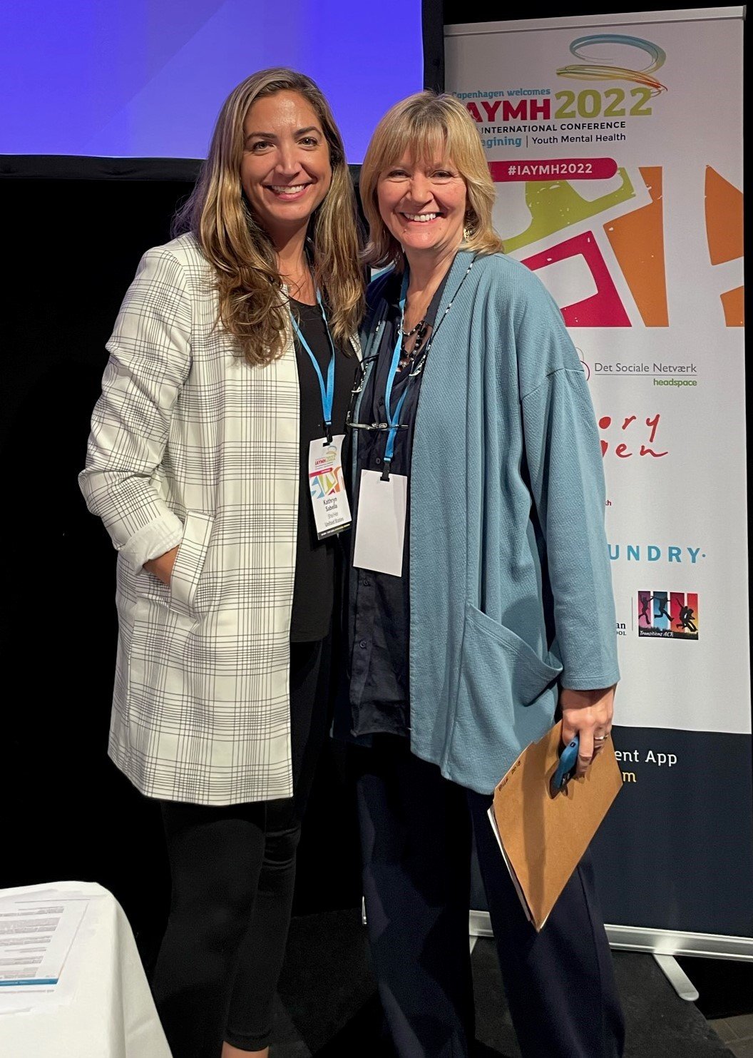 2 white woman smiling at a conference