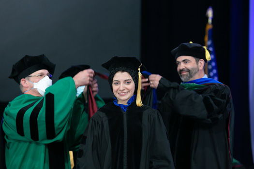 Maggi Ahmed Reffat Aly Ahmed is hooded by David Weaver, PhD and John Harris, MD, PhD.