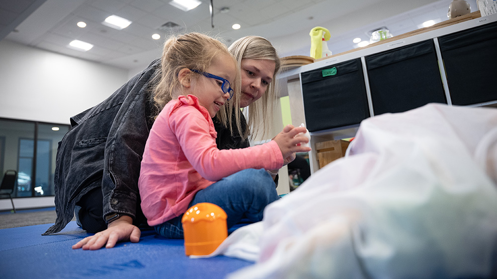 Noa stacks toys with her physical therapist Micayla Pedrick