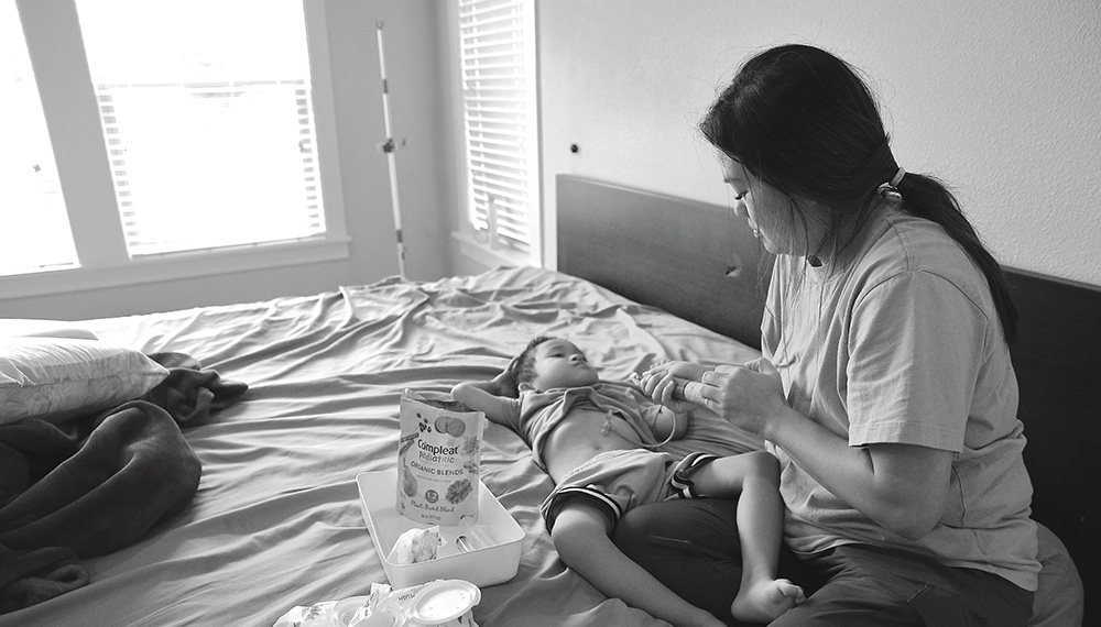 Raiden lies on the bed as his mother, Linda Pham, cares for him