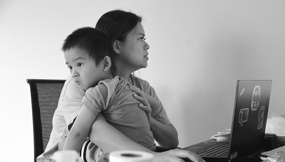 Linda Pham holds her son, Raiden, while working on the computer