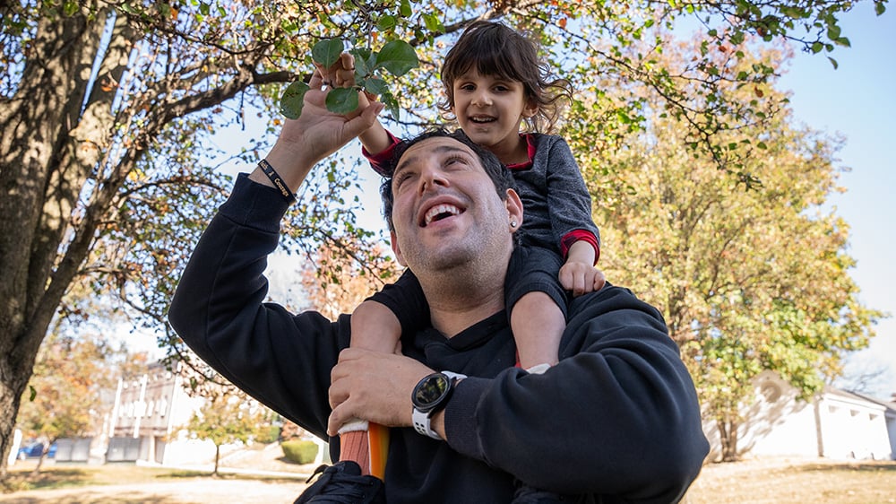 Richie DiGeorge carries his son, Riaan Kaur, on his shoulders