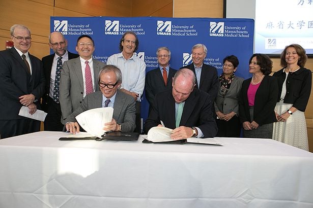 Chancellor Michael F. Collins (left) accepts a generous donation from Li Weibo, as UMass Chan Medical School faculty look on.