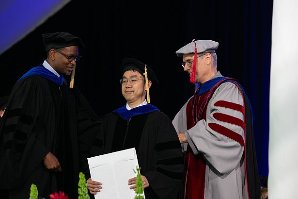 Sungwook Choi of the GSBS is hooded by Brian Lewis and Victor Ambros.