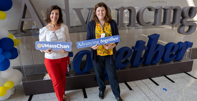 Krisanthi Giaya and Colleen Driskill pose in front of the Advancing Together letters