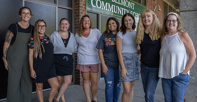 Eight teachers standing together outside a school