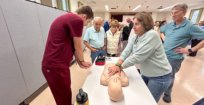 Travis Giragosian showing a group of parishioners how to position their hands during hands-only CPR.