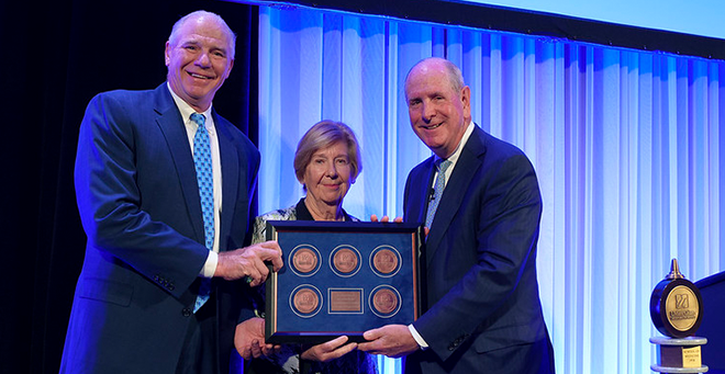 Eric Dickson and Lynda Young on stage with five medallions