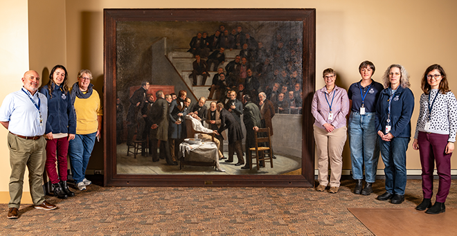 Lamar Soutter Library staff standing on either side of the painting 