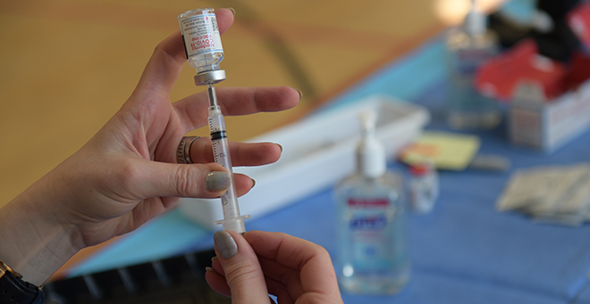 A hand holding a COVID-19 vaccine