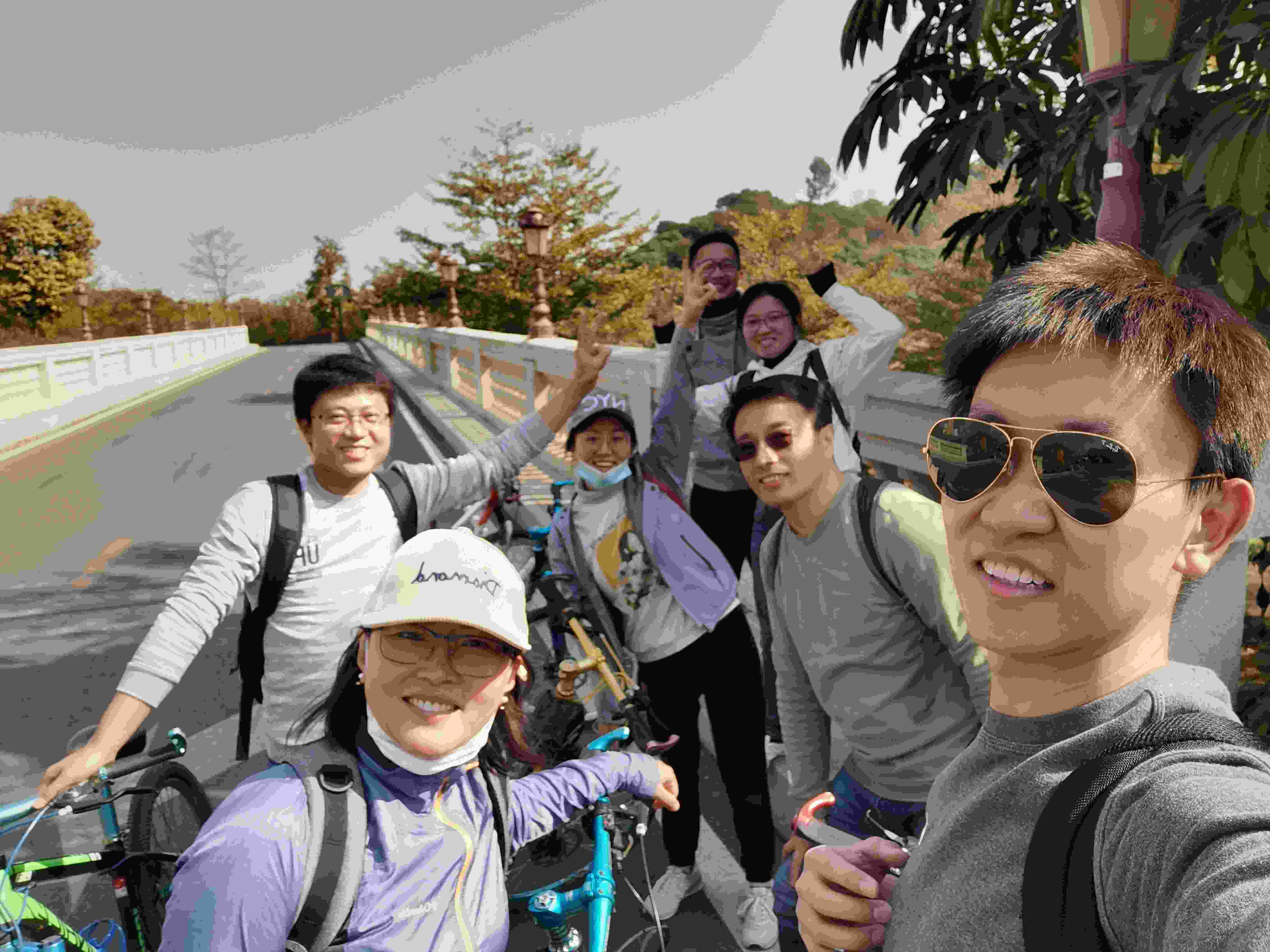 A group of seven smiling people hold bikes for a selfie photoshoot.