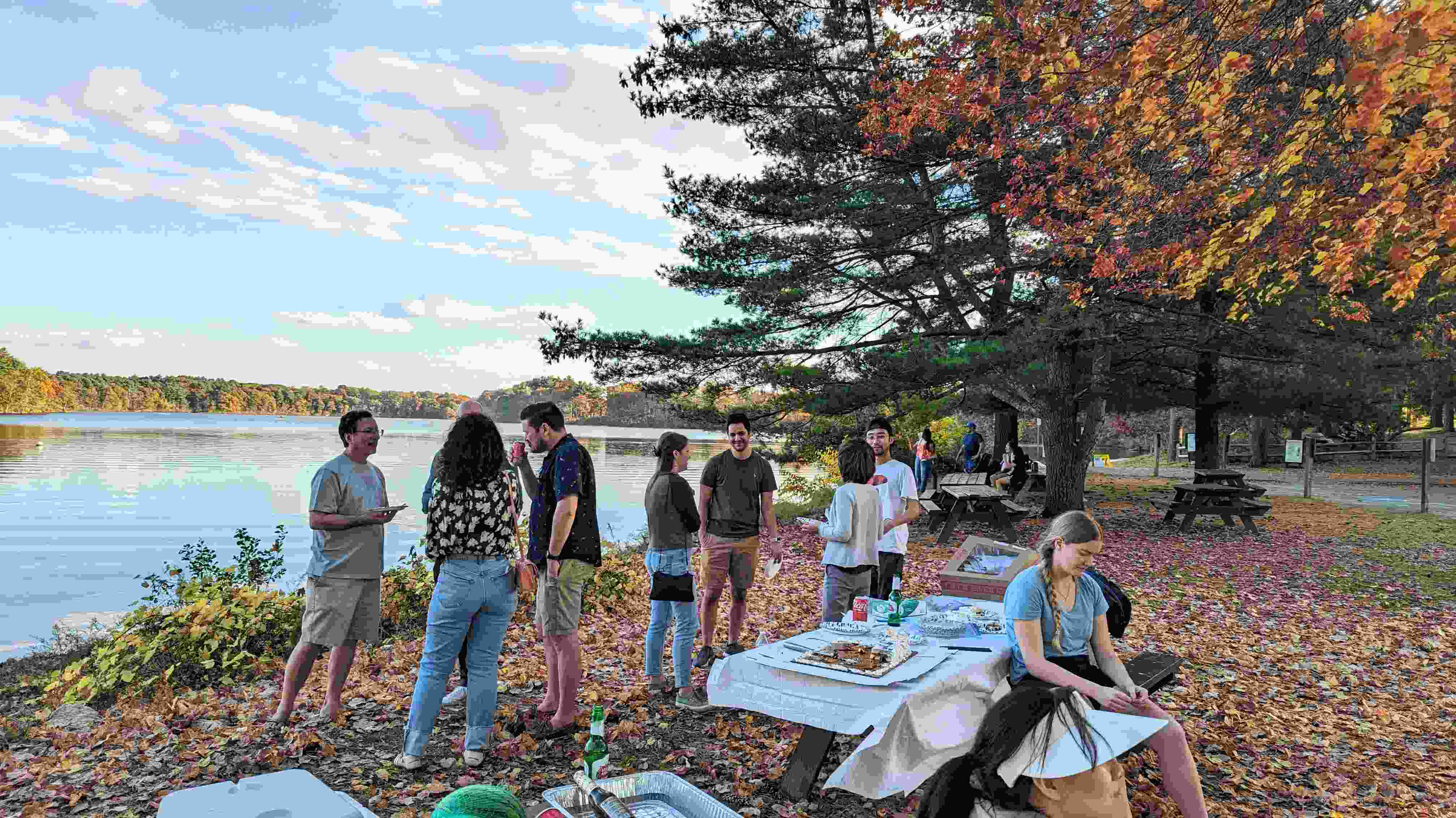 A group of eight people chatting in front of a beautiful lake