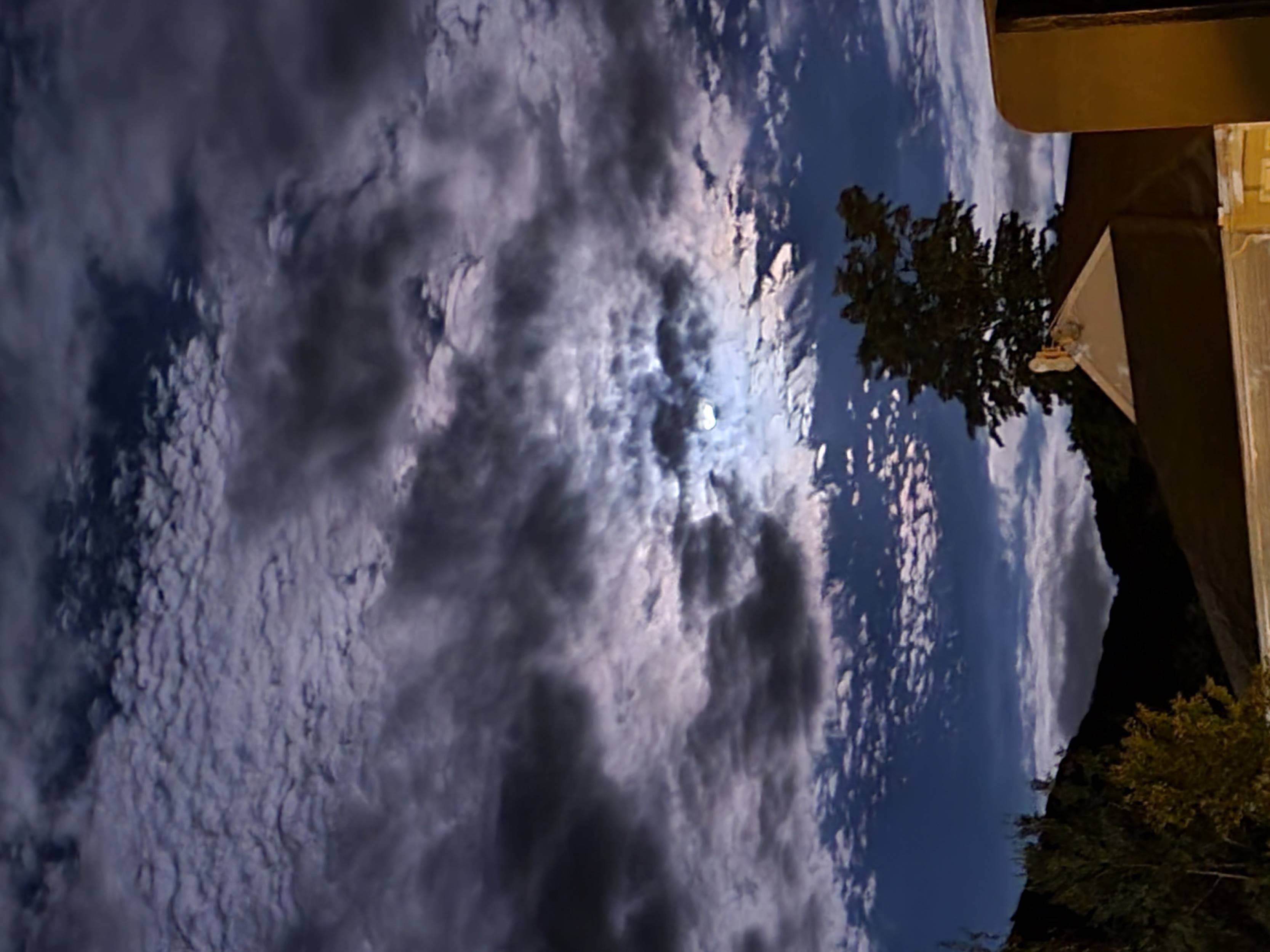 A moonlit night sky with the clouds covering the full moon.